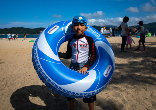 Japanese boy with a huge floating rubber ring on the beach in Amanohashidate, Kyoto Prefecture, Miyazu, Japan