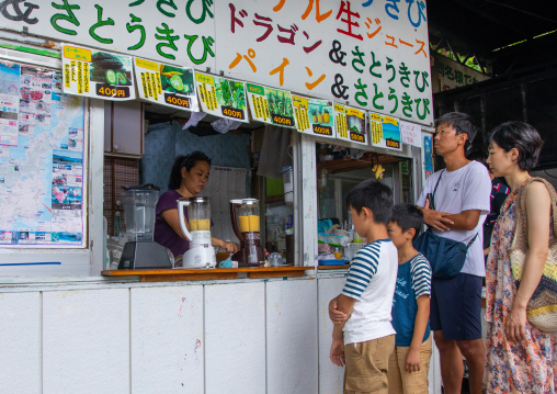 Tourist buying fresh fruit juice in a shop, Yaeyama Islands, Ishigaki-jima, Japan