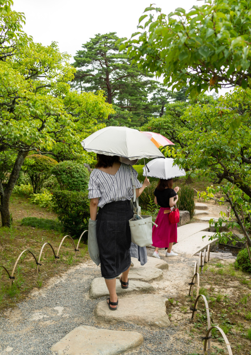 Japanese women walking with umbrellas in Kenroku-en garden, Ishikawa Prefecture, Kanazawa, Japan