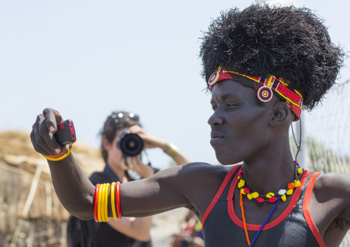 Turkana tribesman taking pictures in front of tourists, Turkana lake, Loiyangalani, Kenya