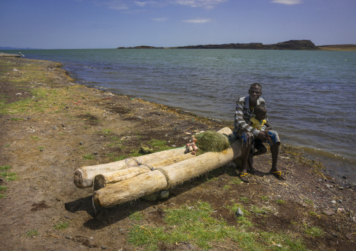Man with his child sit on an el-molo tribe fishing raft, Turkana lake, Loiyangalani, Kenya