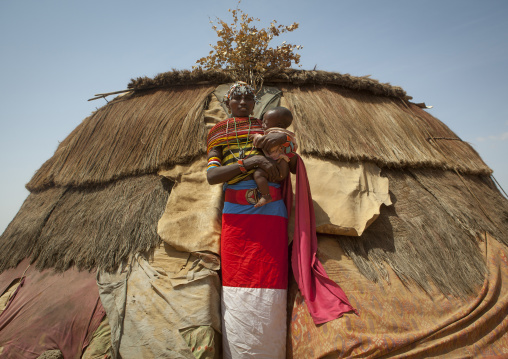 Rendille tribeswoman in front of her hut holding her baby, Marsabit district, Ngurunit, Kenya