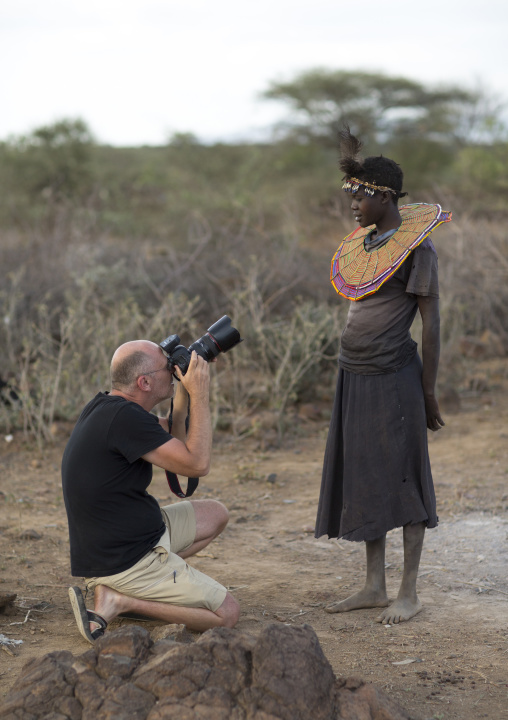 Tourist taking a picture of a pokot woman who wears large necklaces, Baringo county, Baringo, Kenya