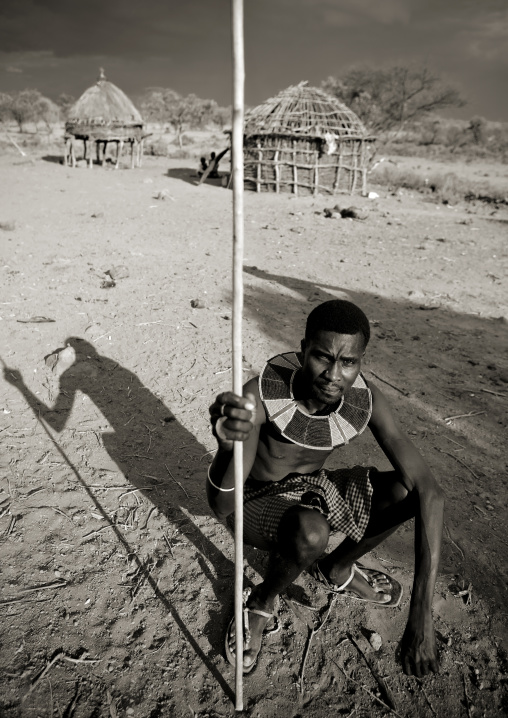Portrait of a Pokot tribe man sit on his wooden pillow holding a spear, Baringo County, Baringo, Kenya