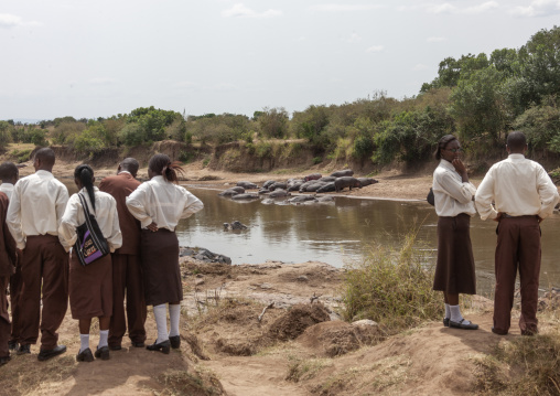 Kenyan pupils watching hippos in a river, Rift Valley Province, Maasai Mara, Kenya