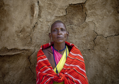 Maasai woman standing in front of an adobe wall, Rift Valley Province, Maasai Mara, Kenya