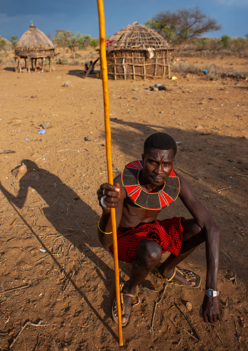 Portrait of a Pokot tribe man sit on his wooden pillow holding a spear, Baringo County, Baringo, Kenya