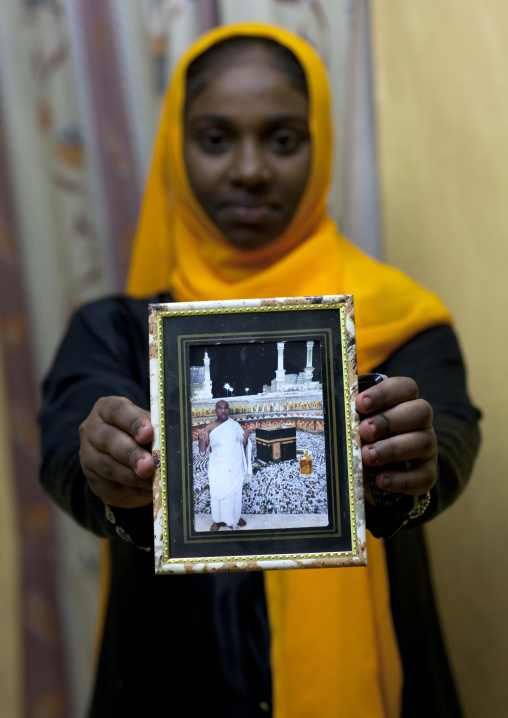 Teenage girl showing picture of father haj to mecca, Lamu County, Lamu, Kenya