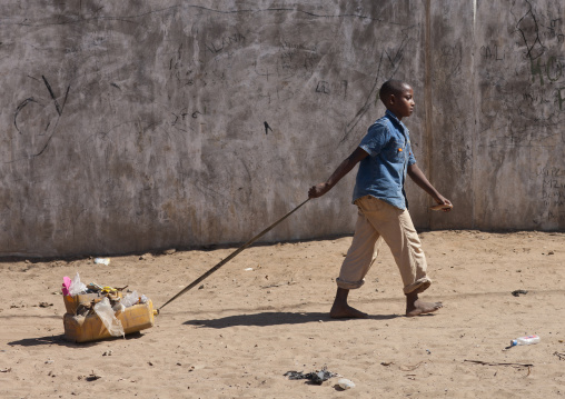 Little boy dragging a toy in a sandy street, Lamu County, Lamu, Kenya