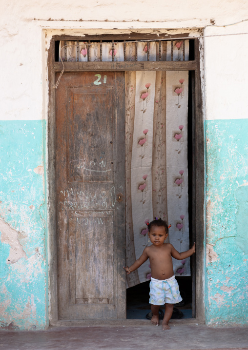 Kenyan girl standing in front of an old wooden door, Lamu County, Lamu, Kenya