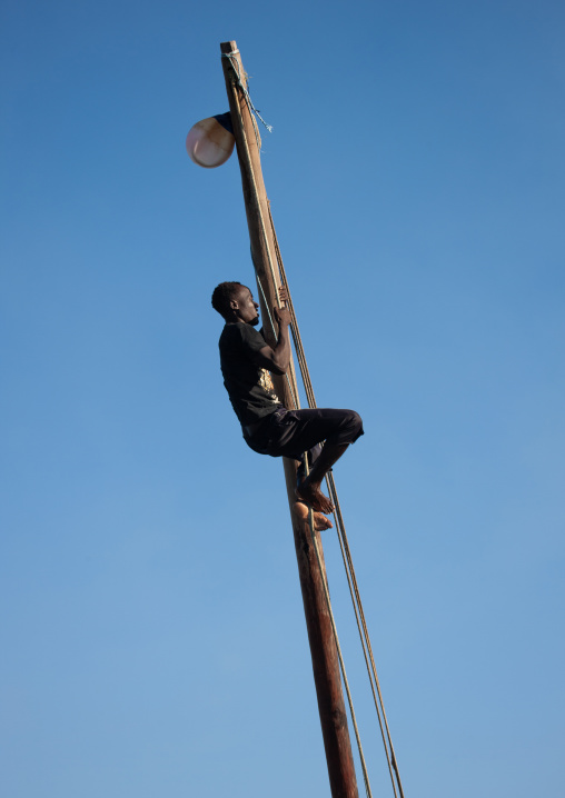 Man climbing a dhow mast, Lamu County, Lamu, Kenya