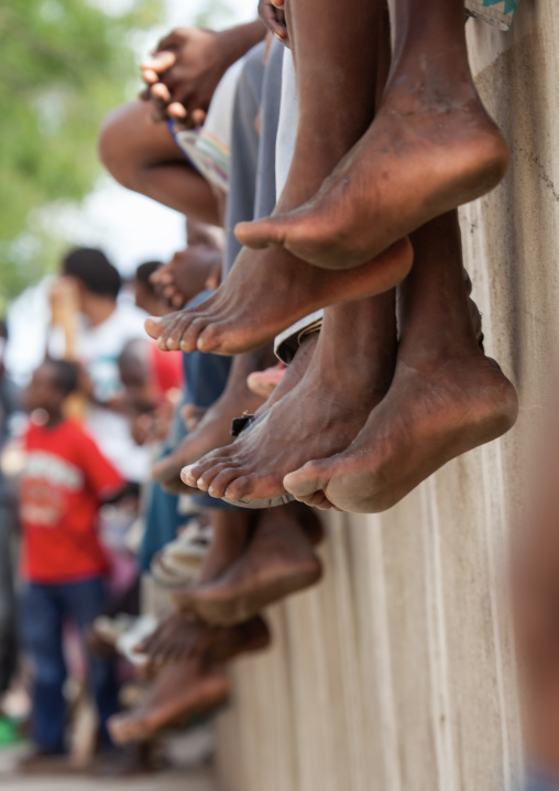 Legs of a bunch of young people sitting on a wall, Lamu County, Lamu, Kenya