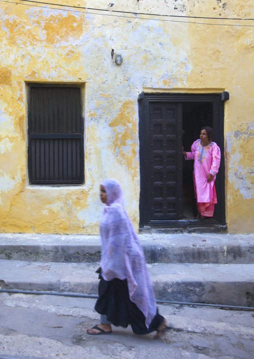 Woman standing in the frame of a wooden carved door, Lamu county, Lamu, Kenya