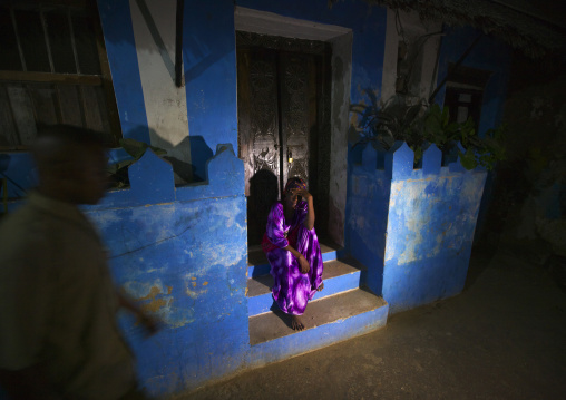 Woman standing on the stairway outside a house by night, Lamu County, Lamu, Kenya