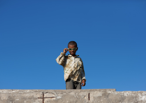 Kenyan boy with sunglasses against blue sky, Lamu County, Lamu, Kenya