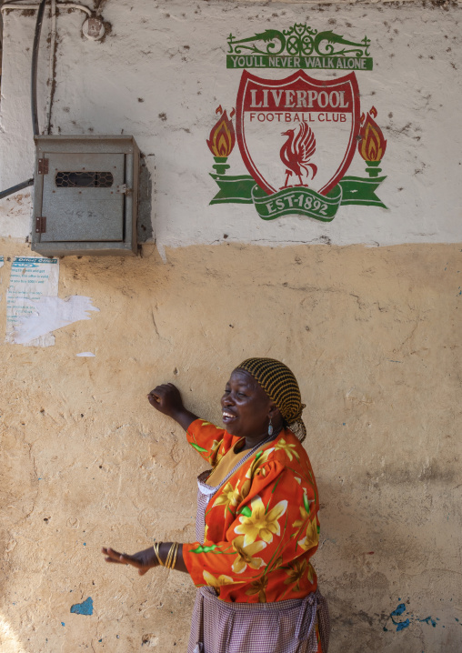 Kenyan woman below a Liverpool football club logo on a house, Lamu County, Lamu, Kenya
