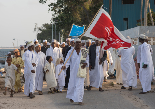 Sunni muslim people parading with flags during the maulidi festivities in the street, Lamu county, Lamu town, Kenya