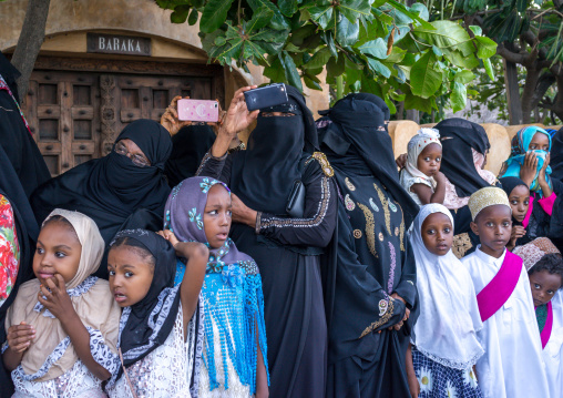 Sunni muslim women taking pictures during the maulidi festivities in the street, Lamu county, Lamu town, Kenya
