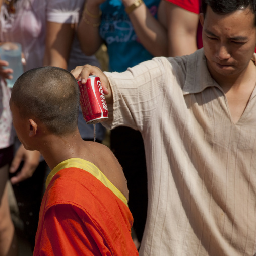 Man putting water ona monk during pii mai lao new year celebration, Luang prabang, Laos