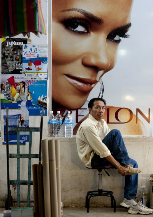 Man in front of a revlon advertisement, Vientiane, Laos