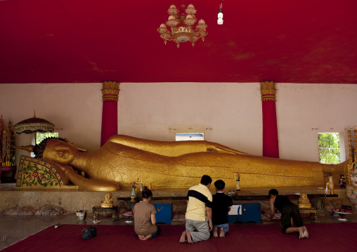 People praying in front of lying buddha statue, Pha bat monastery, Pakse, Laos