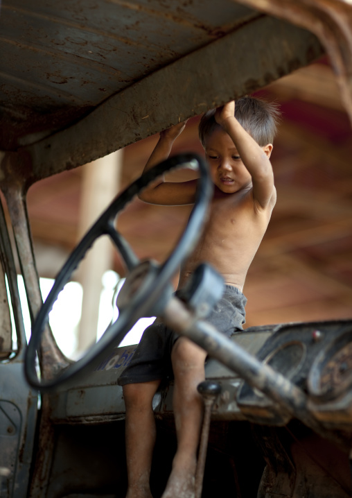 Kid playing in an old car, Thakhek, Laos