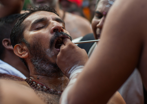 A Devotee Cheek Is Pierced With A Big Skewer By A Priest At Thaipusam Hindu Festival At Batu Caves, Southeast Asia, Kuala Lumpur, Malaysia