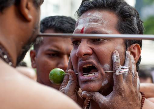 A Devotee Cheek Is Pierced With A Skewer By A Priest At Thaipusam Hindu Festival At Batu Caves, Southeast Asia, Kuala Lumpur, Malaysia