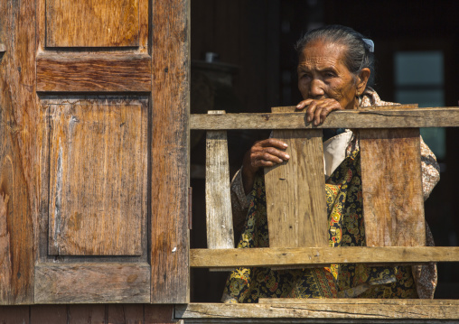 Burmese Woman Looking Out Of Stilt House Window, Inle Lake, Myanmar