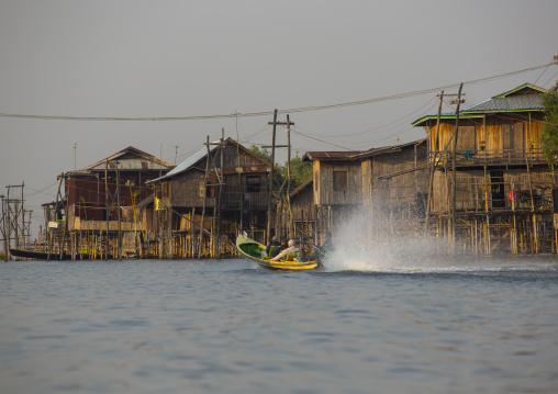 Long Tail Boat Passing In Front Of A Typical House On Stilts, Inle Lake, Myanmar