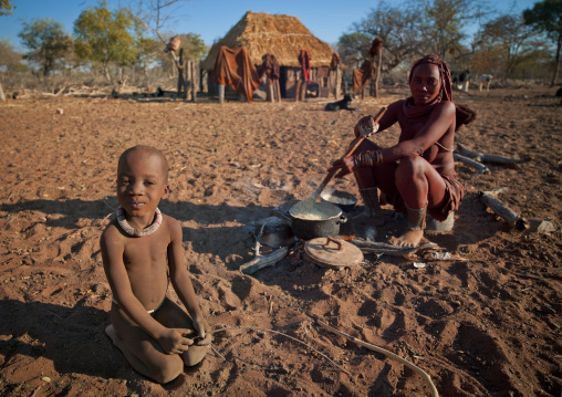 Himba Boy With His Mother Preparing The Meal, Village Of Karihona, Namibia