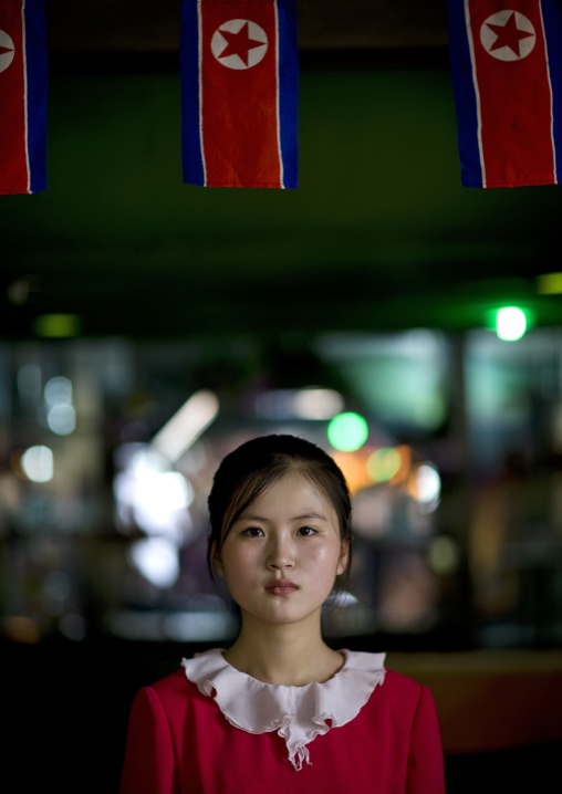 North Korean young woman under North Korean flags, Pyongan Province, Pyongyang, North Korea