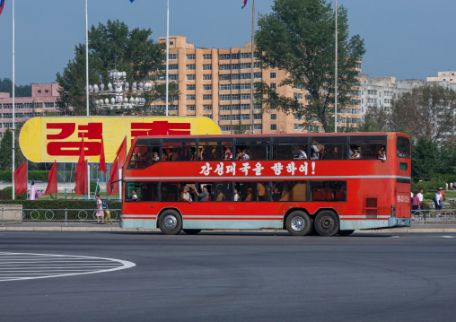 Double deck bus passing in front of a propaganda billboard in the city, Pyongan Province, Pyongyang, North Korea
