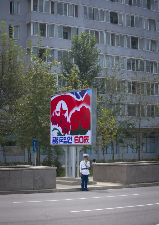 North Korean male traffic security officer in the street under a propaganda billboard, Pyongan Province, Pyongyang, North Korea