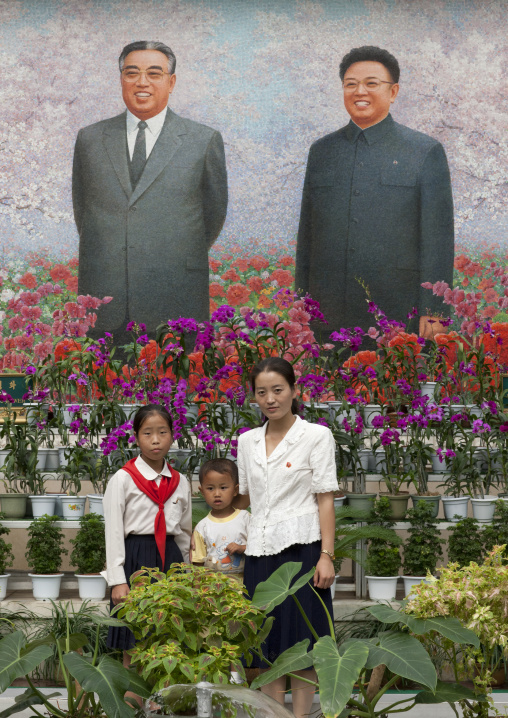 North Korean family posing in front of the Dear Leaders fresco at the international Kimilsungia and Kimjongilia festival, Pyongan Province, Pyongyang, North Korea
