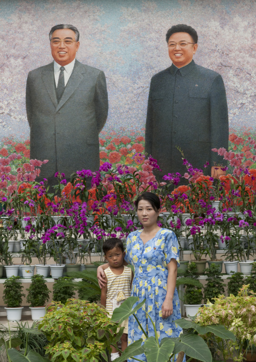 North Korean woman posing in front of the Dear Leaders fresco at the international Kimilsungia and Kimjongilia festival, Pyongan Province, Pyongyang, North Korea