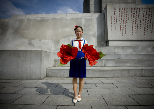 North Korean pioneer girl with flowers ready for the parade in front of the Juche tower, Pyongan Province, Pyongyang, North Korea
