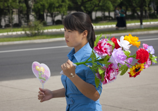 North Korean woman in the street with flowers going to a parade, Pyongan Province, Pyongyang, North Korea