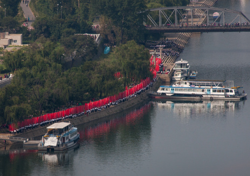 North Korean men parading with red flags along Taedong river for the celebration of the 60th anniversary of the regim, Pyongan Province, Pyongyang, North Korea