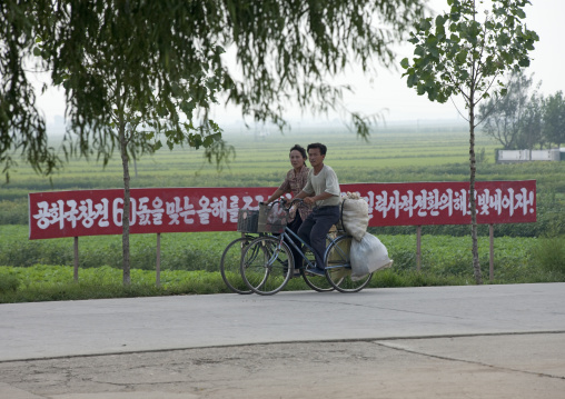 North Korean couple carrying bags on their bicycles in the countryside, Kangwon Province, Chonsam Cooperative Farm, North Korea