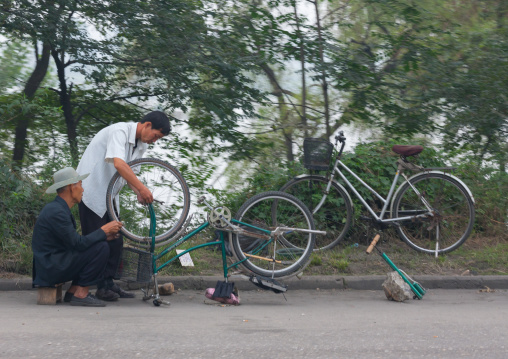 North Korean men repairing bicycles along the road, Pyongan Province, Pyongyang, North Korea