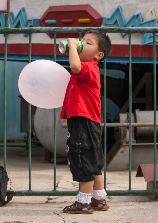 North Korean boy with a balloon drinking in Taesongsan funfair, Pyongan Province, Pyongyang, North Korea