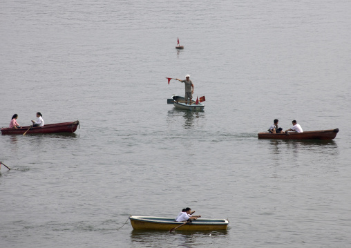 Man monitoring North Korean people in rowing boats on Taedong river, Pyongan Province, Pyongyang, North Korea
