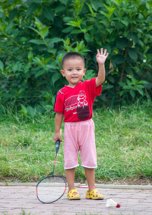 North Korean child waving hand and holding a badminton racket, Pyongan Province, Pyongyang, North Korea