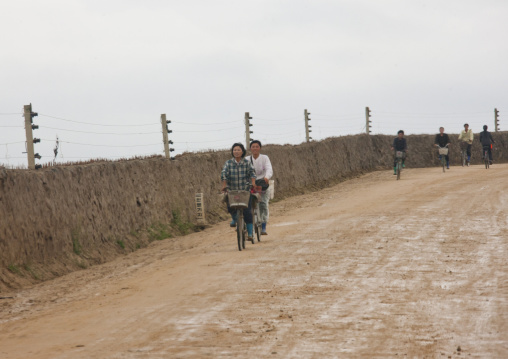 North Korean women cycling along a fenced road, North Hamgyong Province, Chilbosan, North Korea