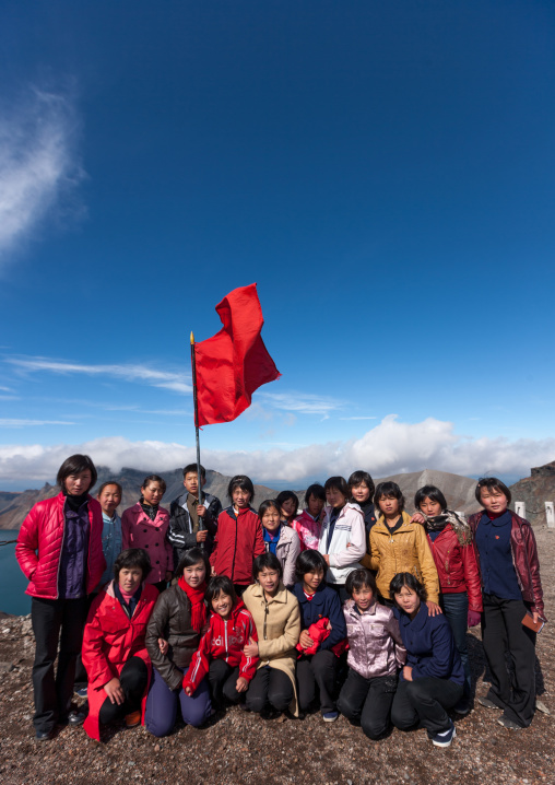 Group of students with red flag in front of lake at mount Paektu, Ryanggang Province, Mount Paektu, North Korea