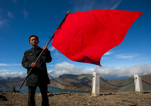 North Korean student holding a big red flag at the top of mount Paektu, Ryanggang Province, Mount Paektu, North Korea