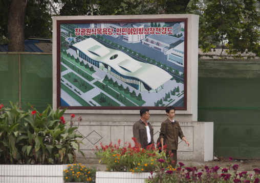 North Korean people walking in front of a billboard advertising construction, Pyongan Province, Pyongyang, North Korea