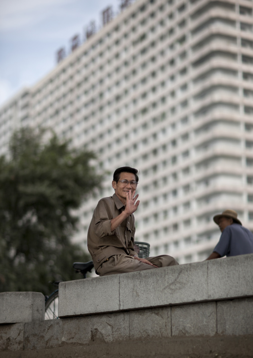 North Korean man sit on a wall waving hand, Pyongan Province, Pyongyang, North Korea
