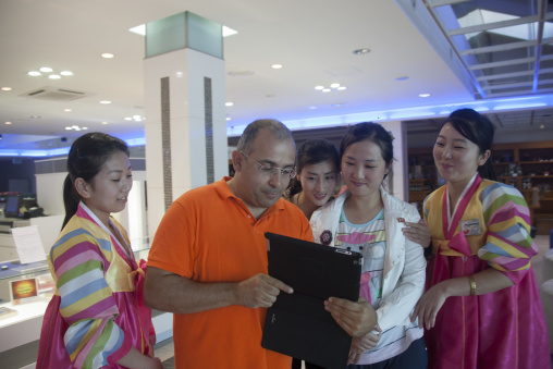 French tourist showing his ipad to saleswomen in the former meeting point between families from North and south, Kangwon-do, Kumgang, North Korea